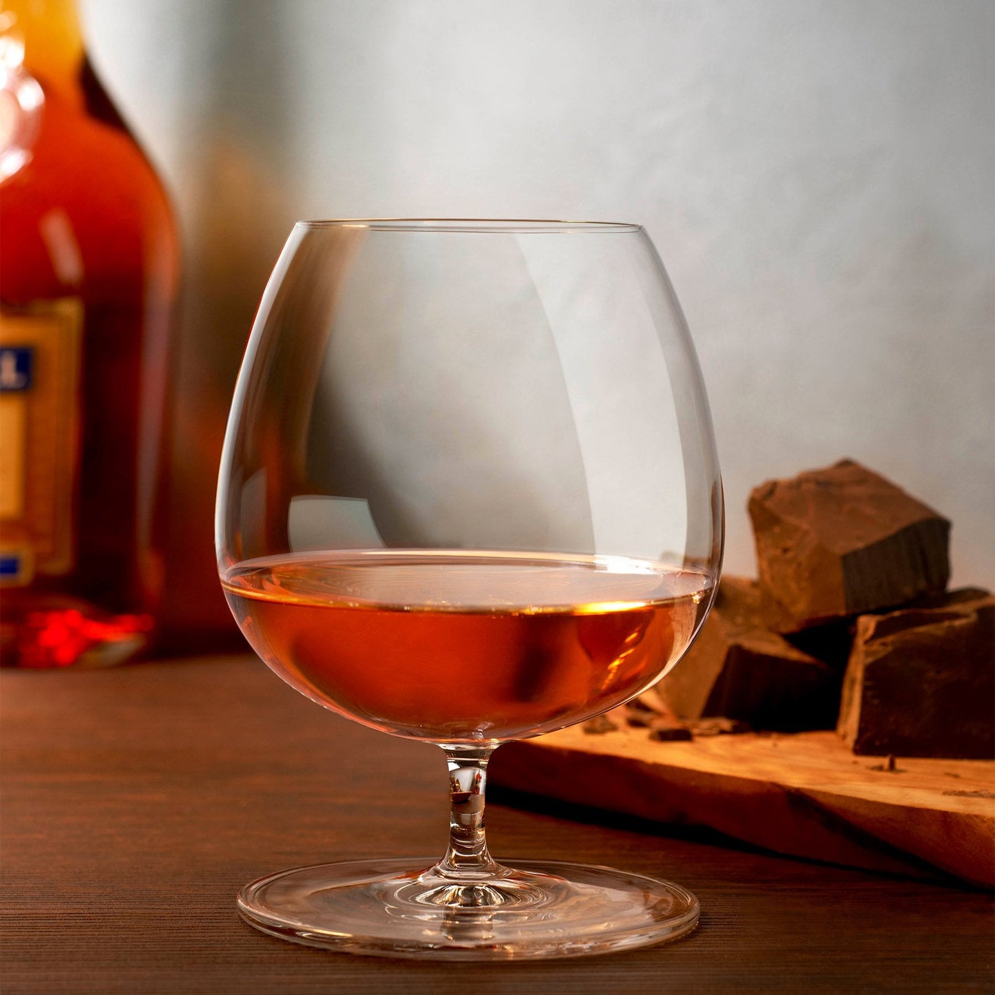 Wide, round-bottomed Cognac glass on a short traditional stem in front of chocolate and dark liquor.