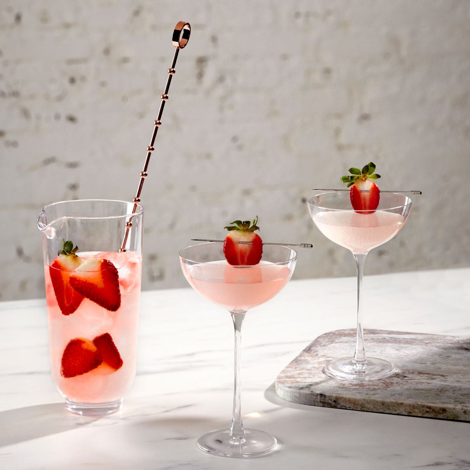 Elegant mixing glass paired with two example strawberry cocktails.